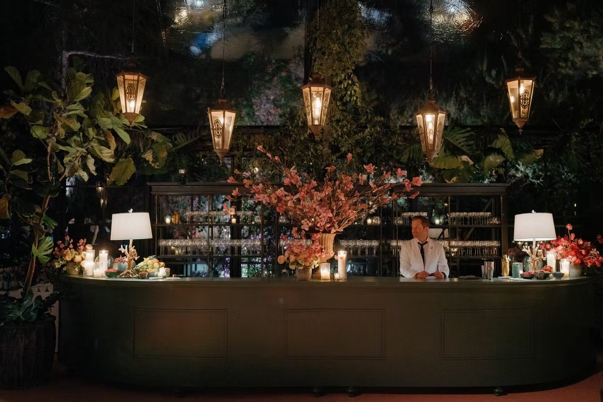 A lantern-lit Bootlegger Bartelier event bar dressed with blossoms and candles